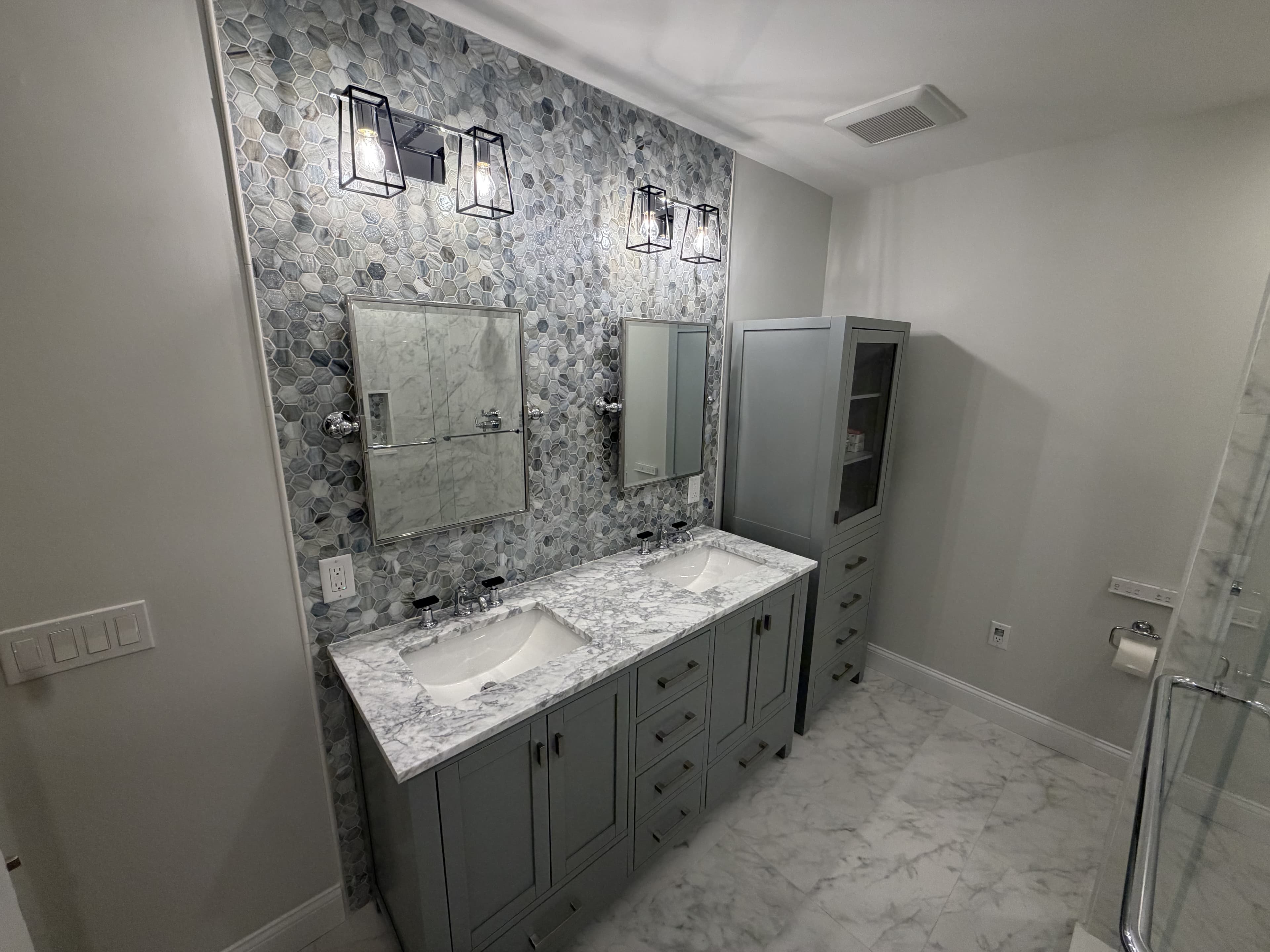 Master bathroom with hexagon mosaic accent wall, double vanity and marble counters